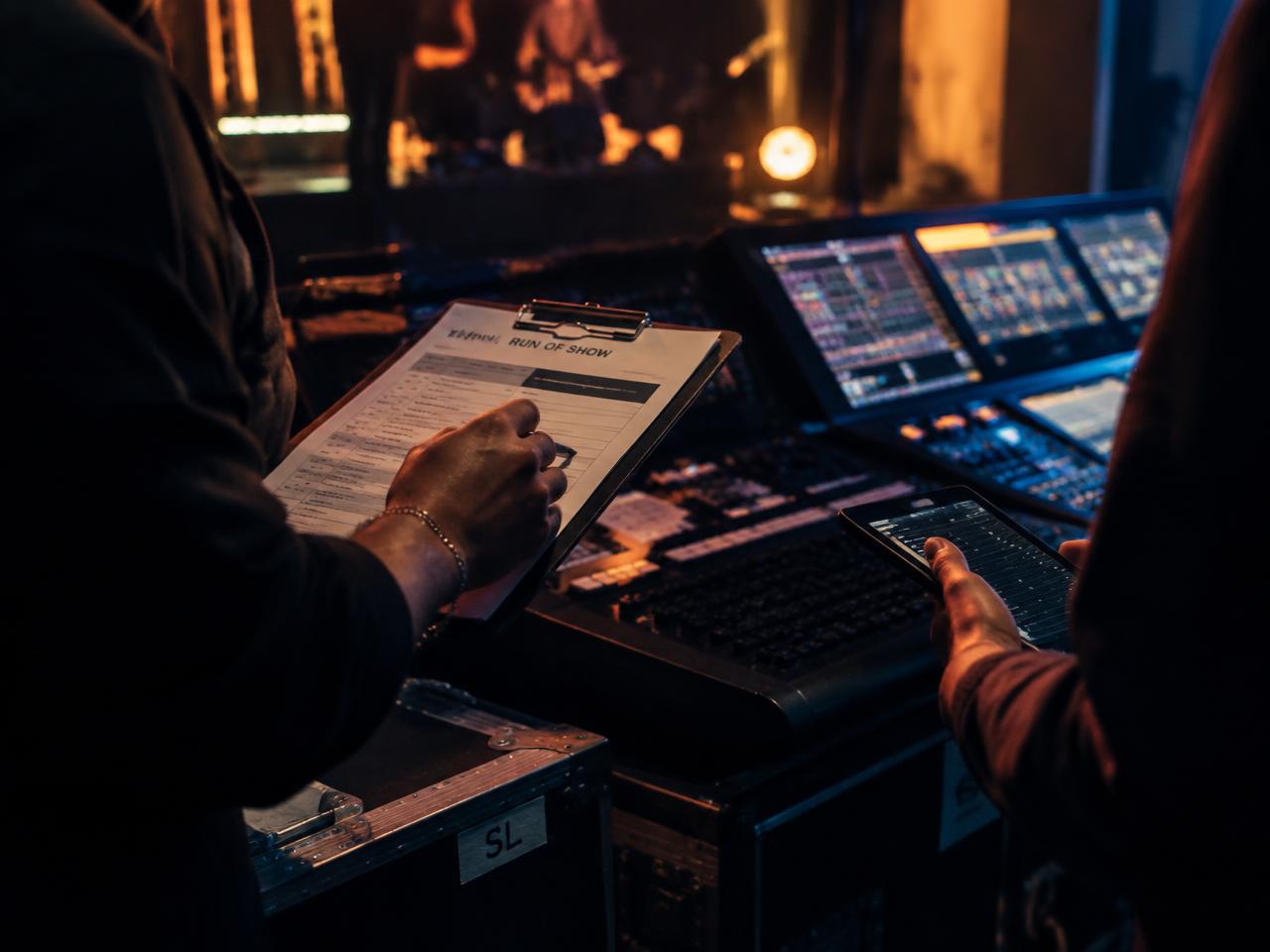 Production team reviewing a run-of-show sheet beside a lighting console